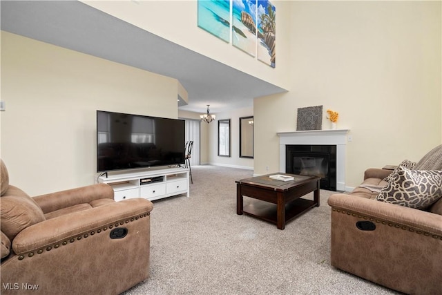 living area with light carpet, baseboards, a notable chandelier, and a glass covered fireplace