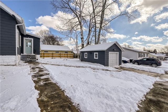 snowy yard featuring a garage and an outbuilding