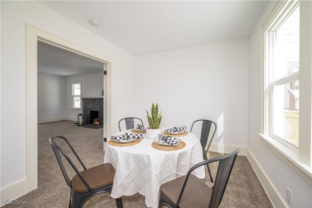 carpeted dining area featuring a fireplace and baseboards