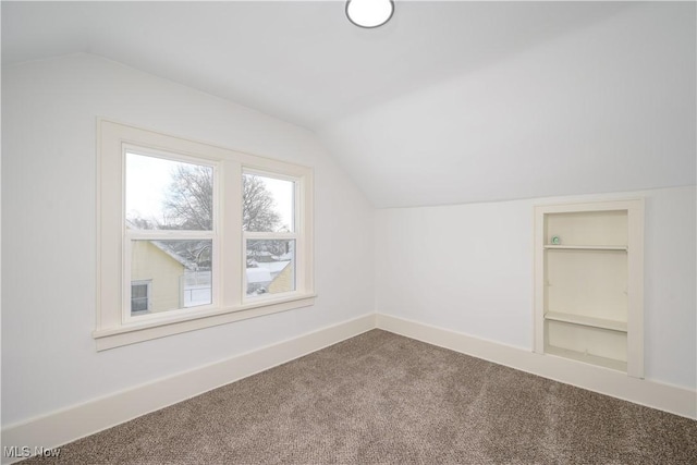 additional living space featuring carpet, built in shelves, baseboards, and vaulted ceiling