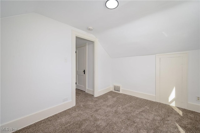 additional living space with carpet floors, lofted ceiling, visible vents, and baseboards