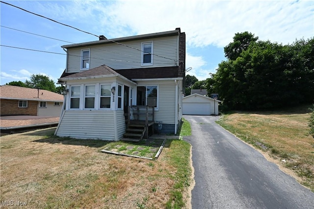 view of front facade with a front yard, a detached garage, aphalt driveway, and an outdoor structure