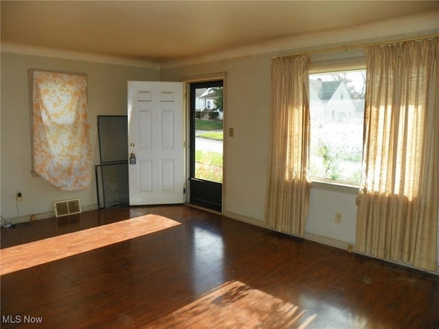 foyer featuring dark wood-type flooring, radiator heating unit, visible vents, and baseboards