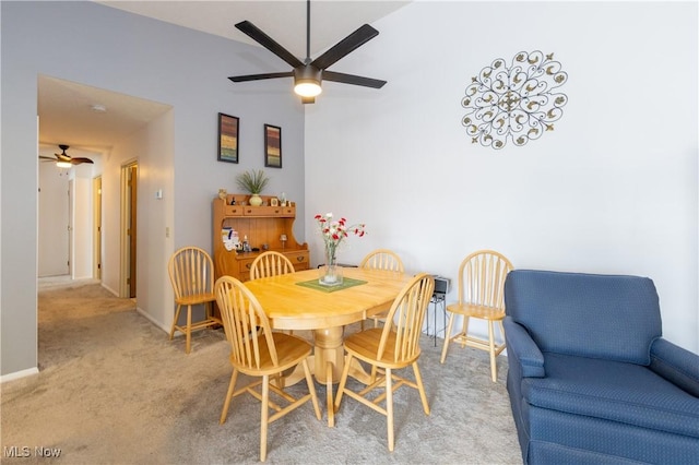 carpeted dining space featuring ceiling fan and baseboards