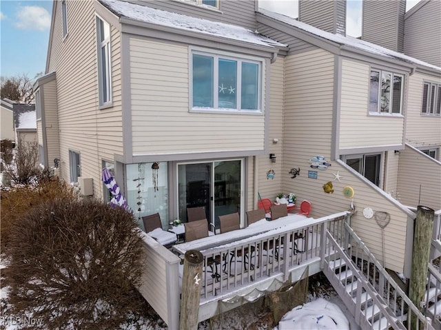 snow covered property with stairway and a chimney