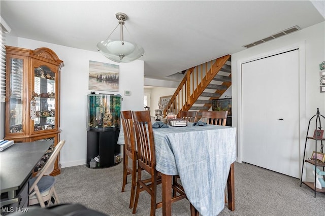 dining room featuring light carpet, baseboards, stairs, and visible vents