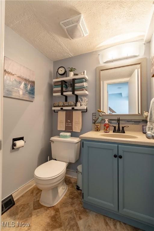 bathroom featuring toilet, visible vents, a textured ceiling, and vanity