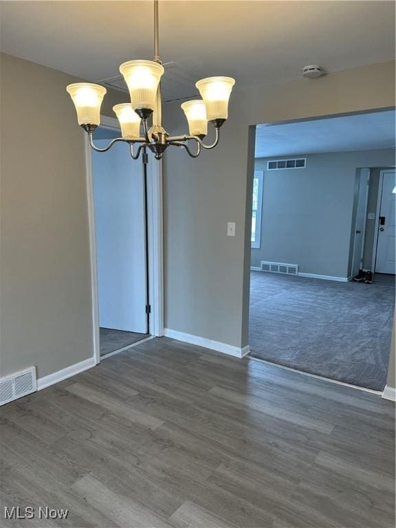 unfurnished room featuring dark wood-style floors, visible vents, and a notable chandelier