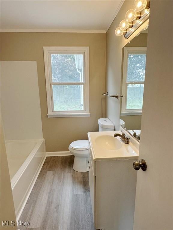 bathroom with toilet, wood finished floors, vanity, baseboards, and ornamental molding