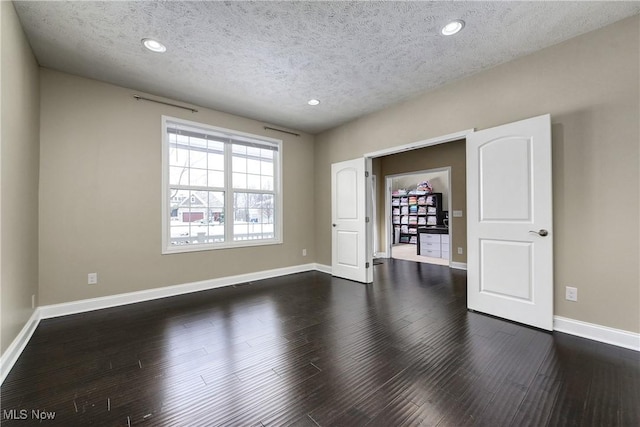 interior space with recessed lighting, dark wood finished floors, a textured ceiling, and baseboards