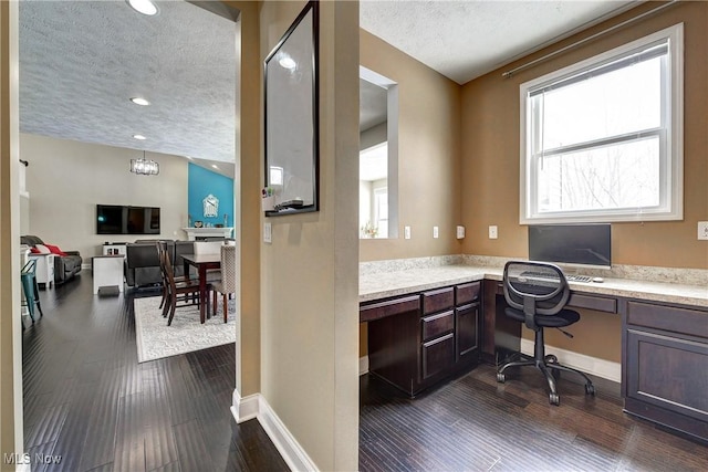 office space featuring baseboards, dark wood-style floors, a textured ceiling, built in desk, and recessed lighting