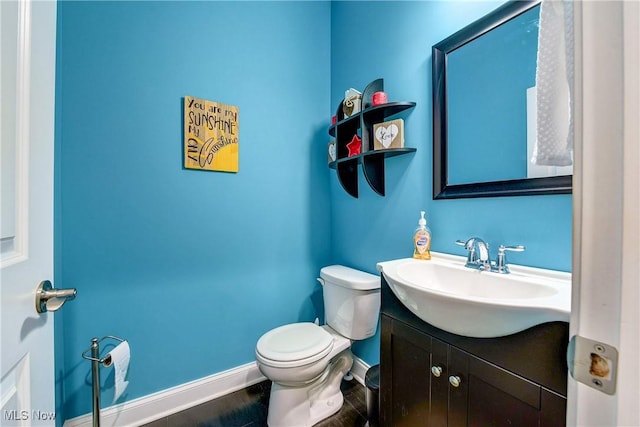 bathroom featuring baseboards, vanity, toilet, and wood finished floors