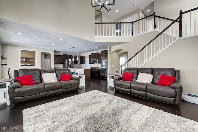 living area featuring arched walkways, a notable chandelier, recessed lighting, stairway, and dark wood finished floors