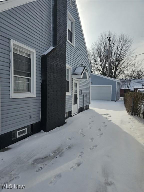 view of snowy exterior with a garage and an outdoor structure