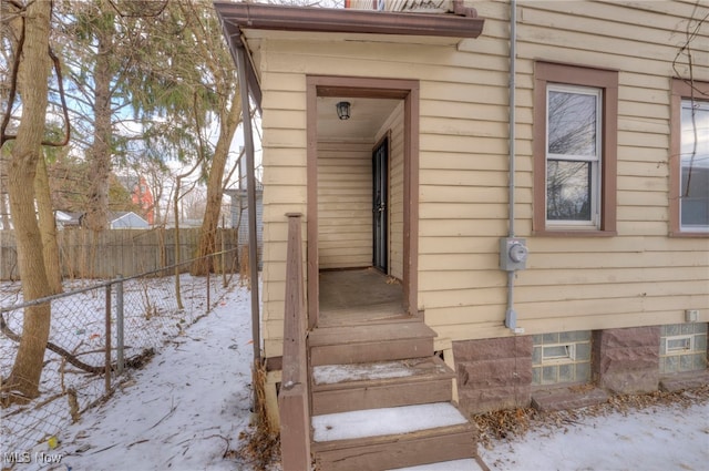 snow covered property entrance with fence