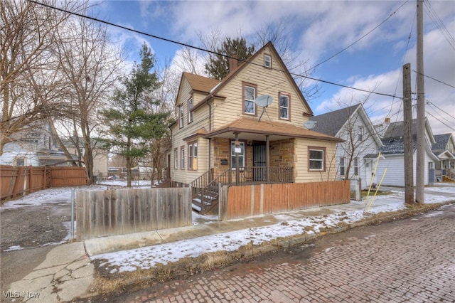 view of front of house featuring a fenced front yard, a chimney, and a porch