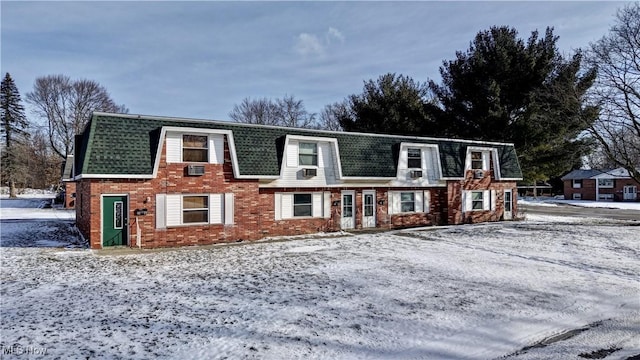 view of front of property featuring brick siding, mansard roof, and a shingled roof