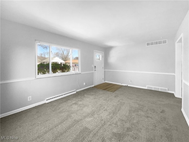 empty room featuring visible vents, a baseboard heating unit, dark colored carpet, and baseboards