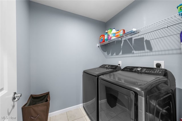 laundry room with light tile patterned floors, laundry area, washing machine and dryer, and baseboards