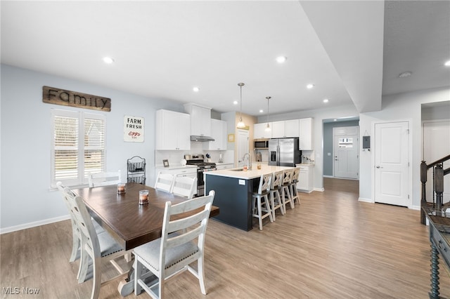 dining space featuring light wood finished floors, stairs, baseboards, and recessed lighting