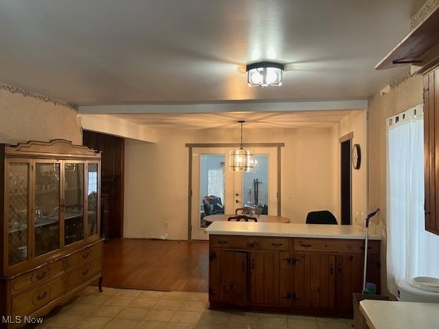 kitchen with light tile patterned floors, light countertops, hanging light fixtures, an inviting chandelier, and a peninsula