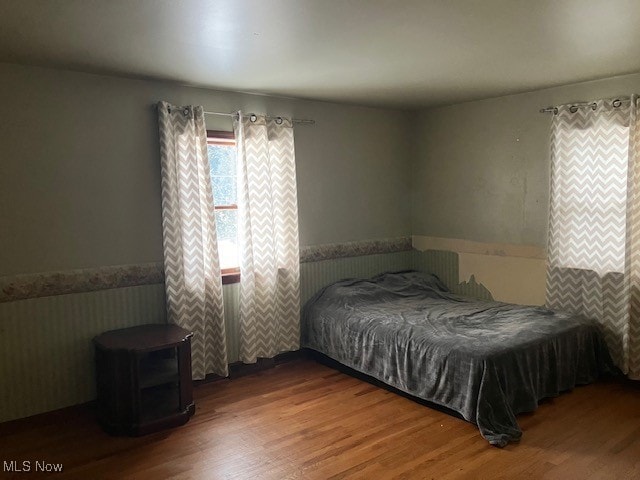 bedroom featuring wainscoting and wood finished floors