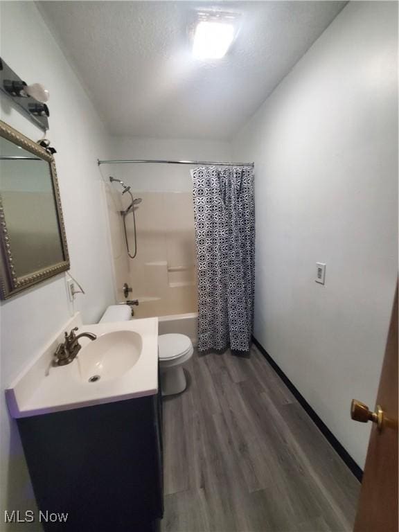 bathroom featuring toilet, wood finished floors, a textured ceiling, vanity, and shower / bath combination with curtain