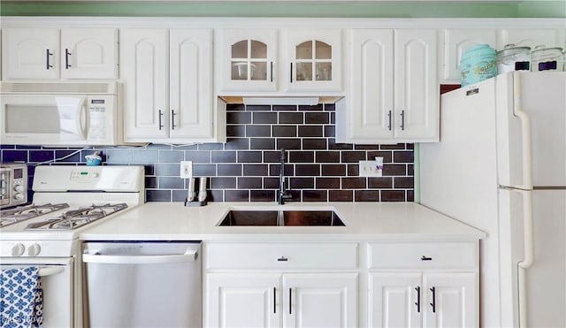 kitchen with white appliances, white cabinetry, light countertops, and a sink