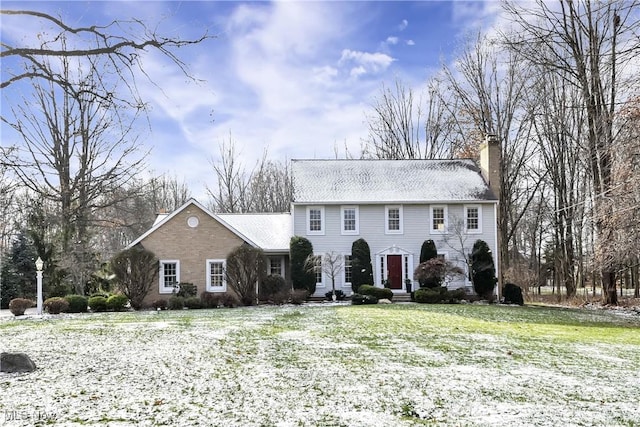 colonial inspired home featuring entry steps, a chimney, and a front lawn