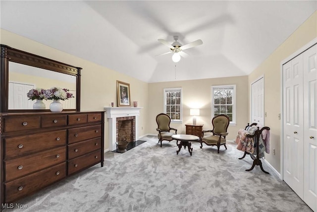 living area with ceiling fan, lofted ceiling, light carpet, a fireplace, and baseboards