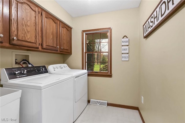 washroom with a sink, visible vents, baseboards, cabinet space, and washer and clothes dryer