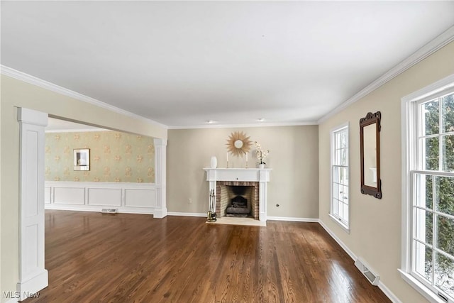 unfurnished living room with visible vents, a fireplace, wood finished floors, and decorative columns