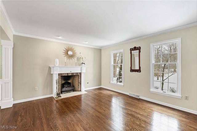 unfurnished living room featuring ornamental molding, a brick fireplace, visible vents, and wood finished floors