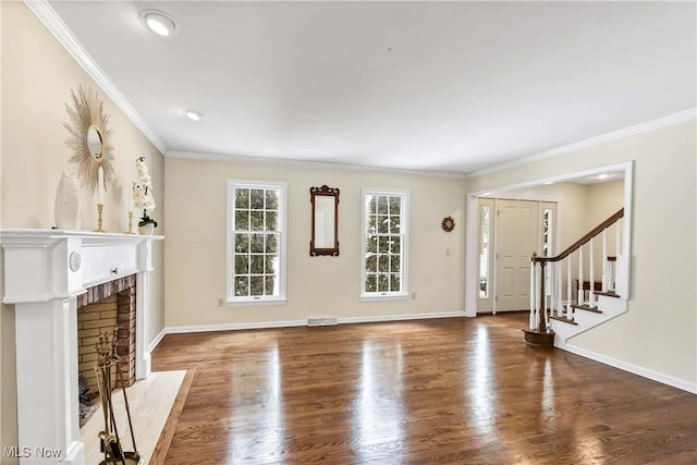 unfurnished living room featuring wood finished floors, visible vents, stairs, a brick fireplace, and crown molding