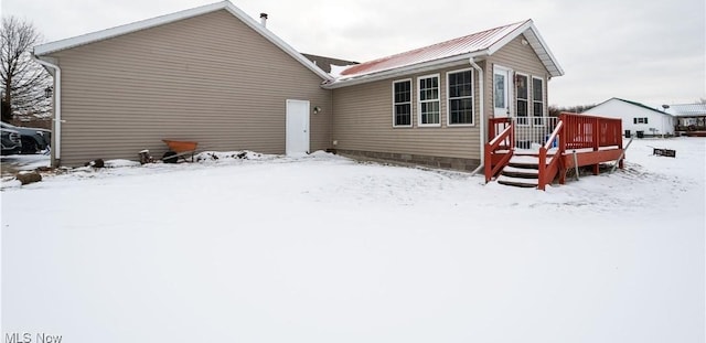 snow covered property with metal roof and a deck