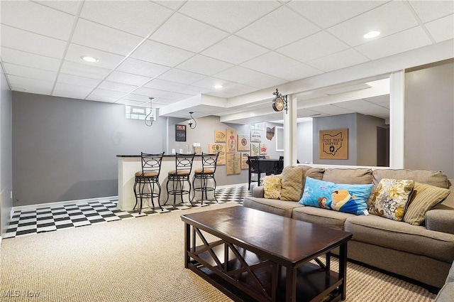 living room featuring a bar, baseboards, a drop ceiling, and recessed lighting