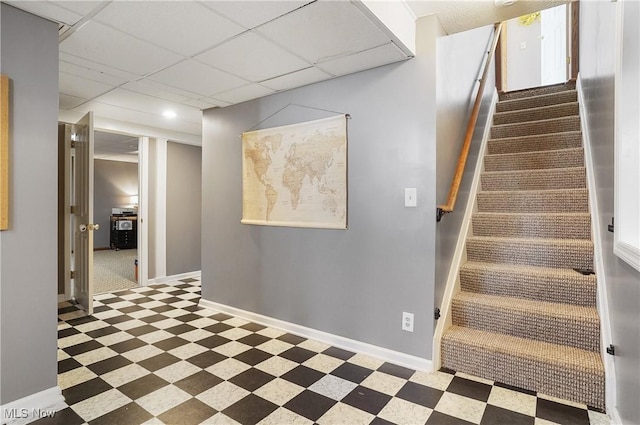 stairway with baseboards, a drop ceiling, and tile patterned floors