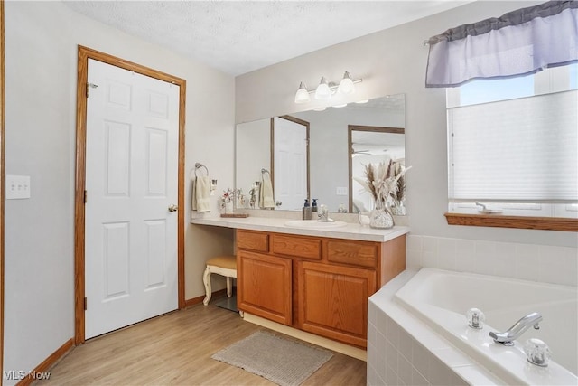 bathroom featuring a garden tub, a textured ceiling, wood finished floors, and vanity