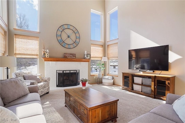 living room featuring a healthy amount of sunlight, a brick fireplace, and light colored carpet