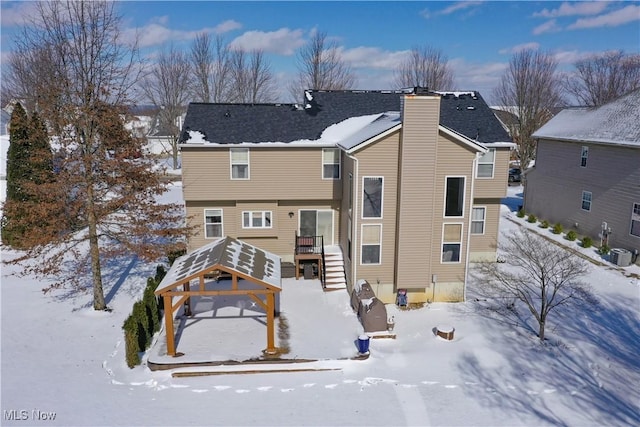 snow covered back of property with a chimney and cooling unit