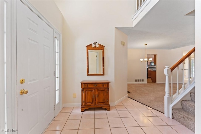 entryway with light tile patterned floors, visible vents, light carpet, and stairs