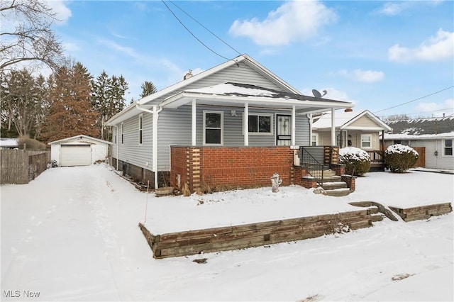 view of front of home featuring a garage, brick siding, and an outbuilding