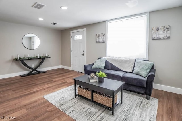 living area featuring visible vents, plenty of natural light, baseboards, and wood finished floors