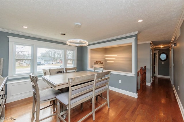 dining space with a textured ceiling, ornamental molding, dark wood finished floors, and baseboards