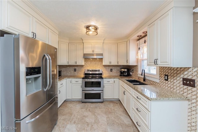 kitchen featuring under cabinet range hood, stainless steel appliances, a sink, light stone countertops, and pendant lighting