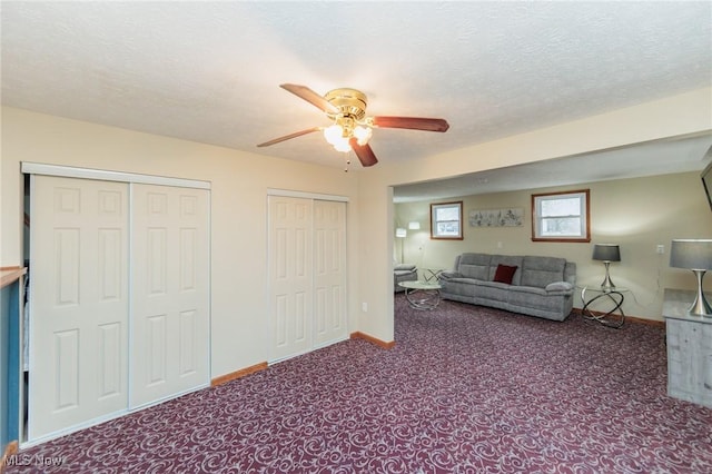 unfurnished living room featuring a ceiling fan, carpet, baseboards, and a textured ceiling