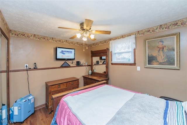 bedroom featuring a textured ceiling, wood finished floors, ceiling fan, and baseboards