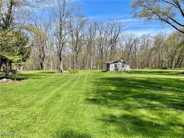 view of yard featuring an outdoor structure and a view of trees