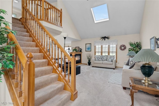 living room with high vaulted ceiling, a skylight, light colored carpet, and stairway