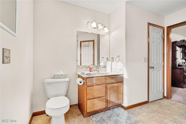 bathroom with toilet, tile patterned floors, vanity, and baseboards